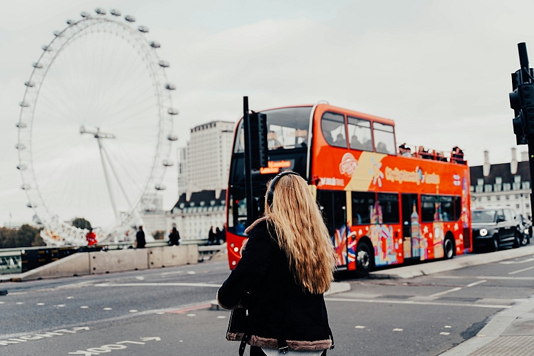 woman walking in london near a sight seeing bus